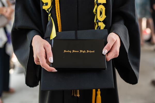 Seeley-Swan High School black and gold diploma jacket held by female hands